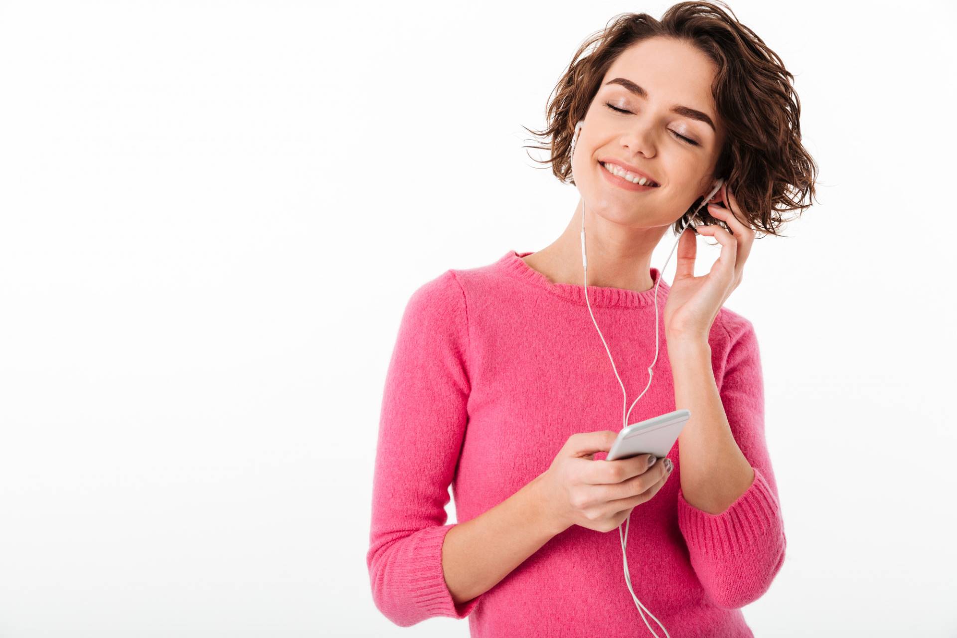 Imagen de una mujer escuchando m&uacute;sica a trav&eacute;s de su smartphone con auriculares